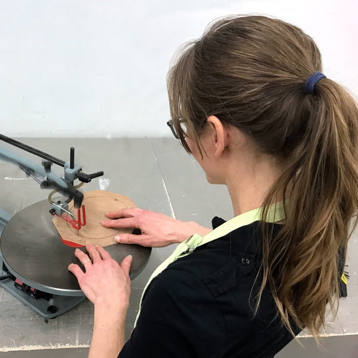 Artist Rebecca Luncan cutting a liner for a custom frame on a scroll saw